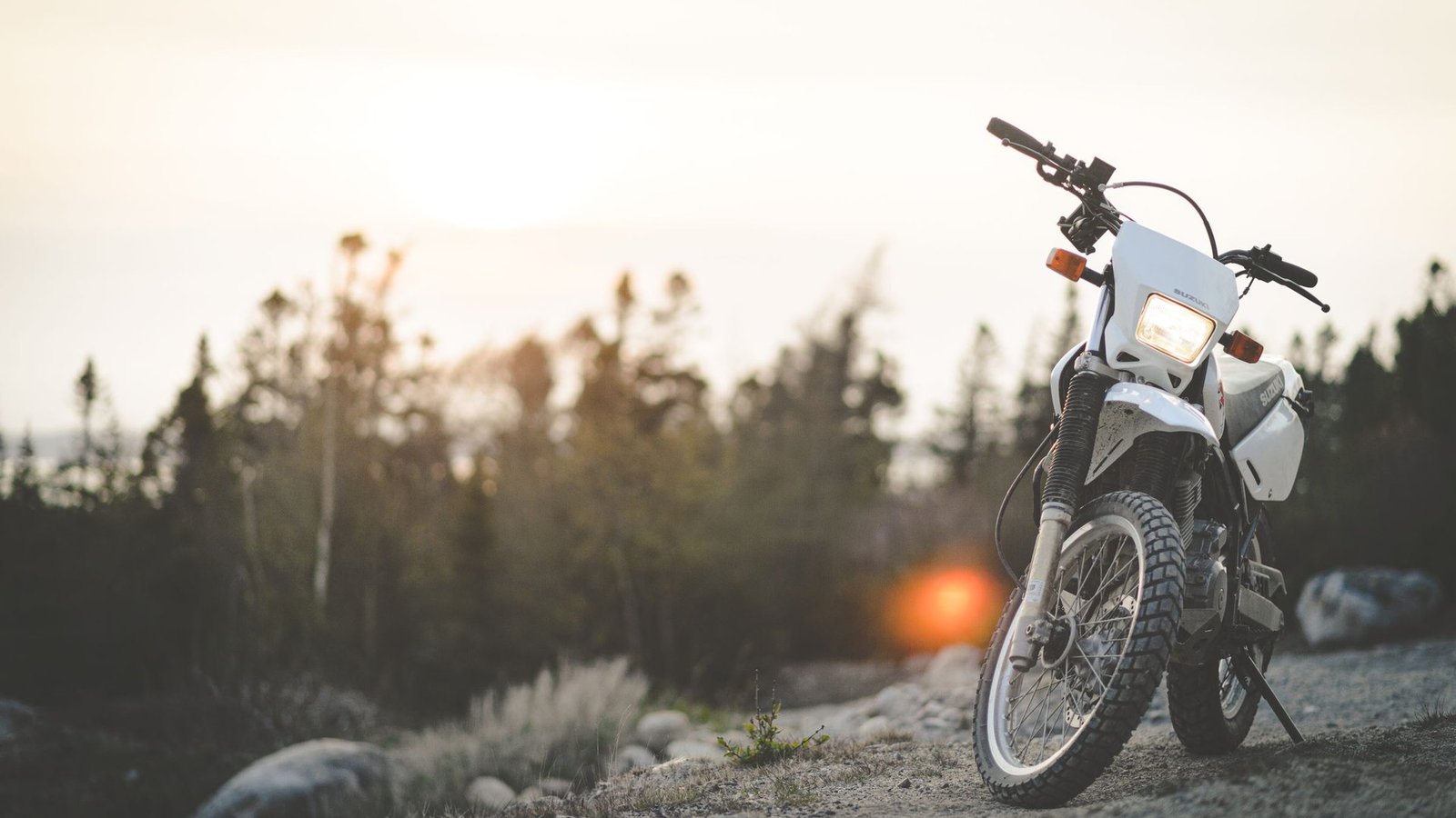 Motorcycles under $8,000 guide: a motorbike parked on a gravel trail with a sunset in the background